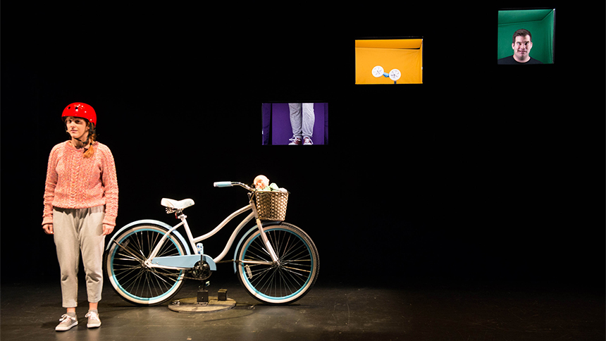 Le personnage principal sur scène avec une bicyclette